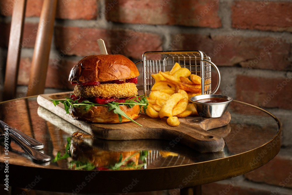 Big cheeseburger with french fries. Hamburger with beef patty onion, tomato, lettuce pickles, melted cheddar, mustards, tomato jam, mayo