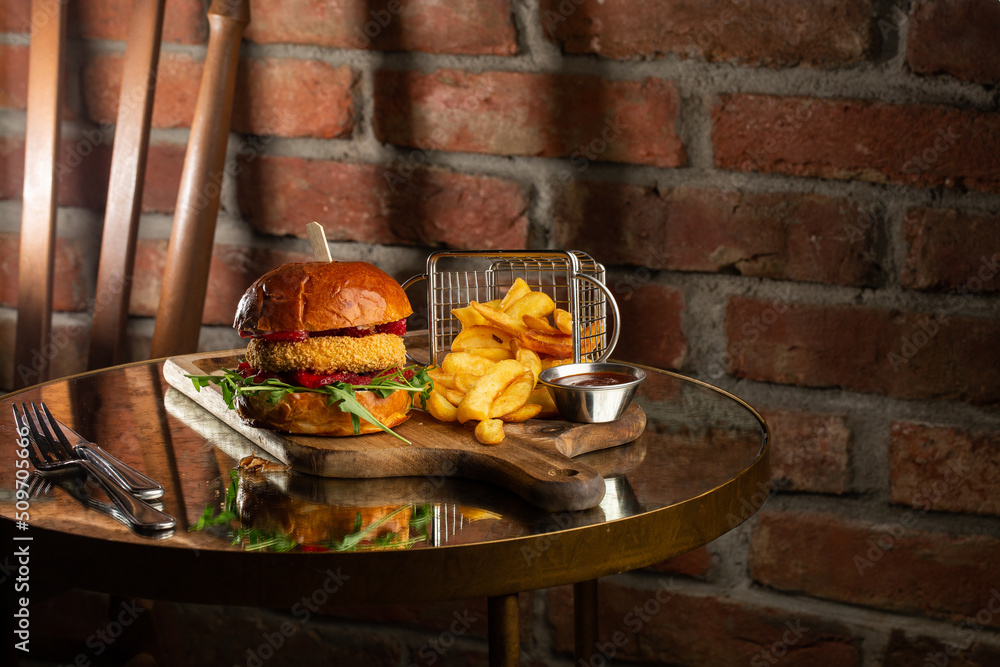 Big cheeseburger with french fries. Hamburger with beef patty onion, tomato, lettuce pickles, melted cheddar, mustards, tomato jam, mayo