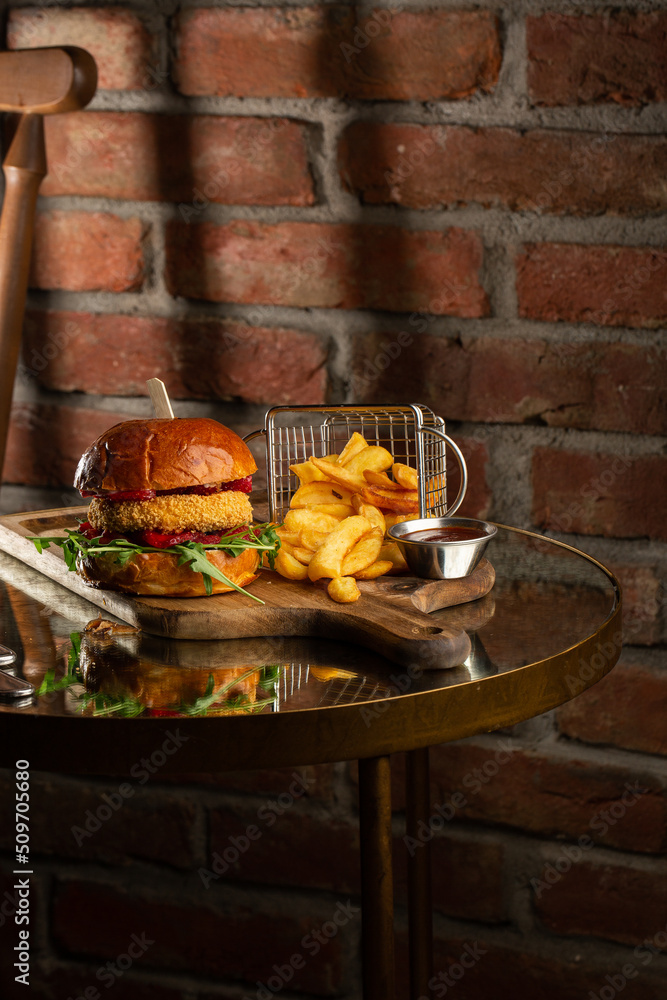 Big cheeseburger with french fries. Hamburger with beef patty onion, tomato, lettuce pickles, melted cheddar, mustards, tomato jam, mayo