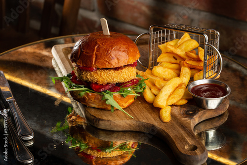 Big cheeseburger with french fries. Hamburger with beef patty onion, tomato, lettuce pickles, melted cheddar, mustards, tomato jam, mayo