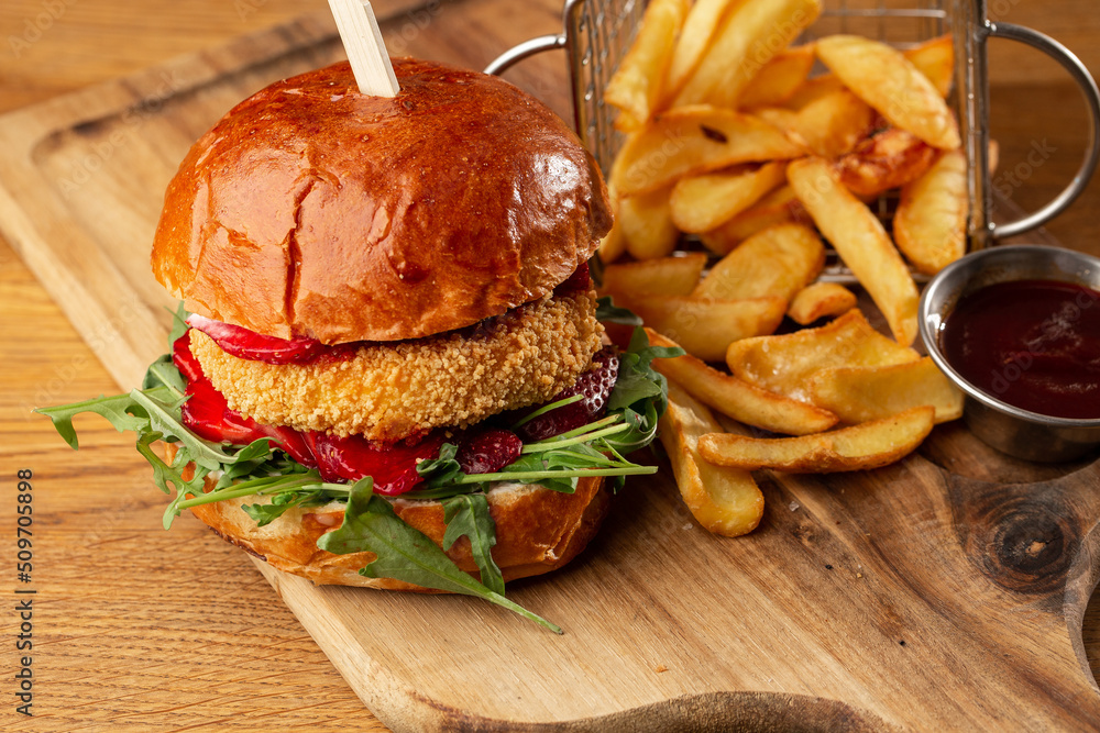 Big cheeseburger with french fries. Hamburger with beef patty onion, tomato, lettuce pickles, melted cheddar, mustards, tomato jam, mayo