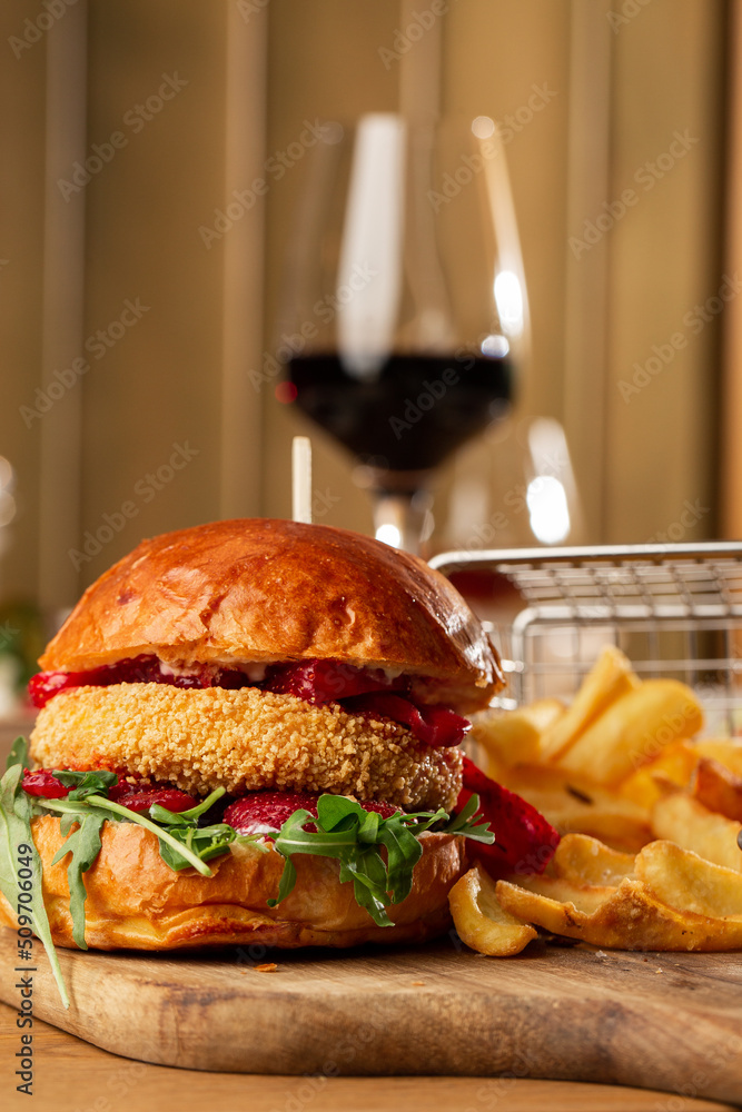 Big cheeseburger with french fries. Hamburger with beef patty onion, tomato, lettuce pickles, melted cheddar, mustards, tomato jam, mayo