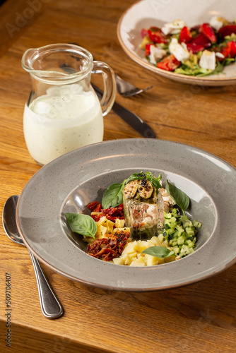 Obraz na płótnie Closeup of cold soup okroshka with beef, vegetables and kefir served in a white bowl, selective focus. Summer, cold soup with cucumber, radish, egg, potatoes and fresh herbs seasoned with kefir. w salonie