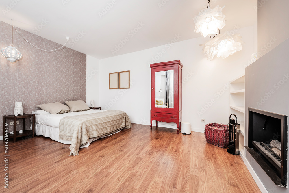 Obraz premium Double room decorated with wallpaper, red painted wardrobe with mirror, double bed and wood burning fireplace