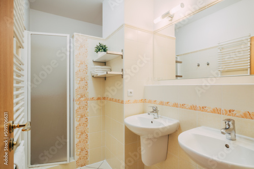 Small ordinary bathroom with retro tiles in an older hotel room. Everything is beautifully clean. The bathroom has common equipment such as whasbasins  mirrors  lamps and so on. The doors are wooden.