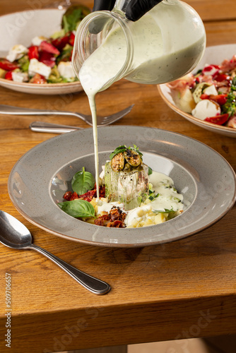 Obraz na płótnie Closeup of cold soup okroshka with beef, vegetables and kefir served in a white bowl, selective focus. Summer, cold soup with cucumber, radish, egg, potatoes and fresh herbs seasoned with kefir. w salonie