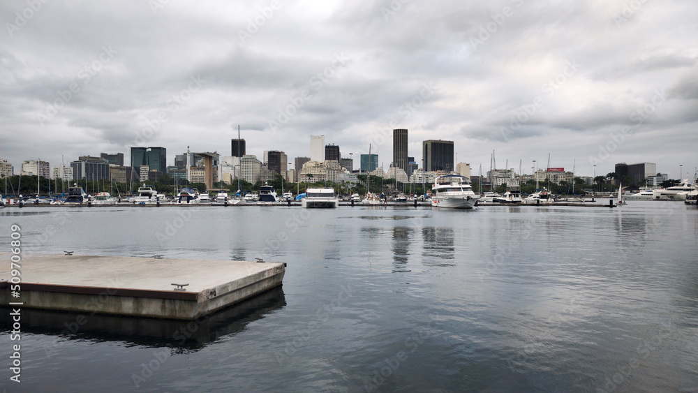 Naklejka premium Yacht Club marina harbor ramp sea water bay vessel sailboat boat motorboat pier bench balcony restaurant bar parking cement path stone texture Rio de Janeiro