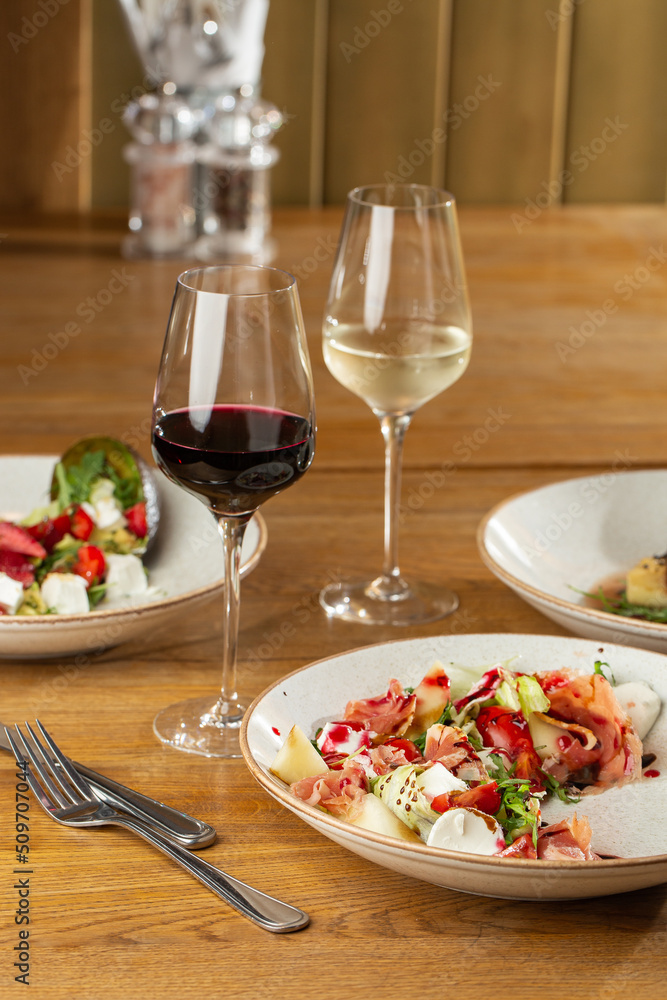 Prosciutto crudo ham salad with mozzarella cheese and arugula on a plate. Bright background. Top view. Copy space