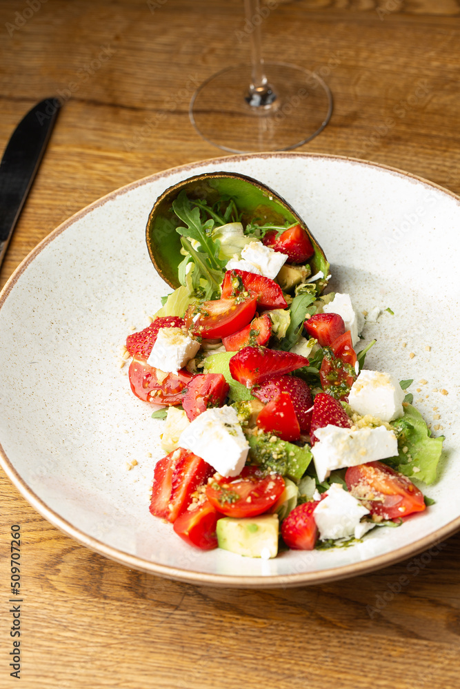 Tasty and healthy salad with arugula, brie cheese, avocado, cherry tomatoes and strawberry. Top view. The flat lay. Banner