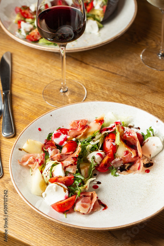 Obraz na płótnie Prosciutto crudo ham salad with mozzarella cheese and arugula on a plate. Bright background. Top view. Copy space w salonie