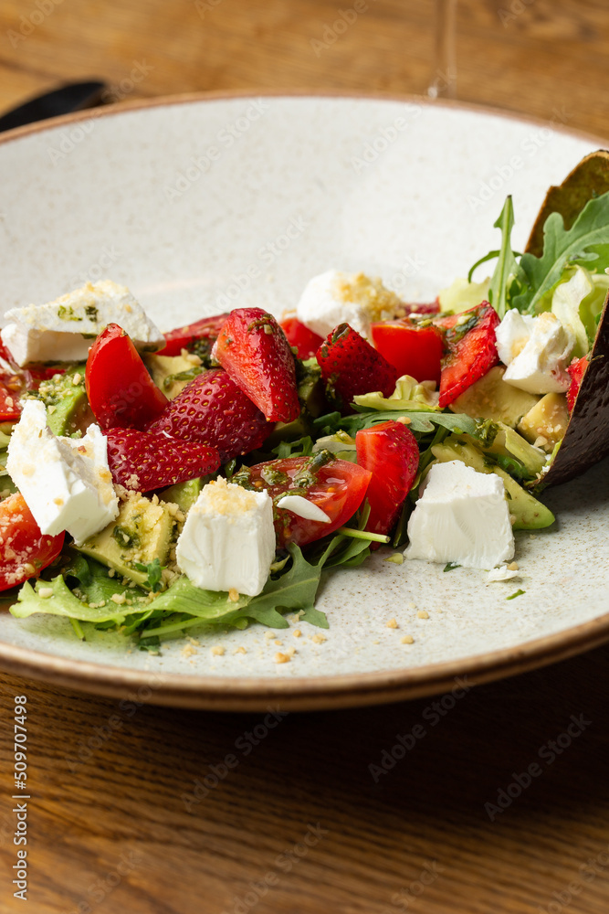 Tasty and healthy salad with arugula, brie cheese, avocado, cherry tomatoes and strawberry. Top view. The flat lay. Banner