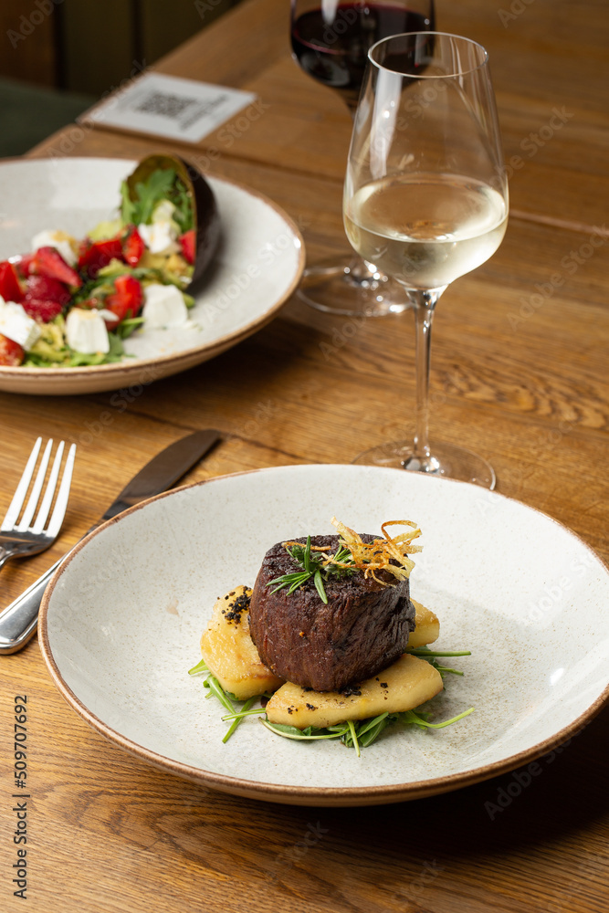 Grilled meat fillet steak medallion with green sauce, served with pear or apple. On dark background