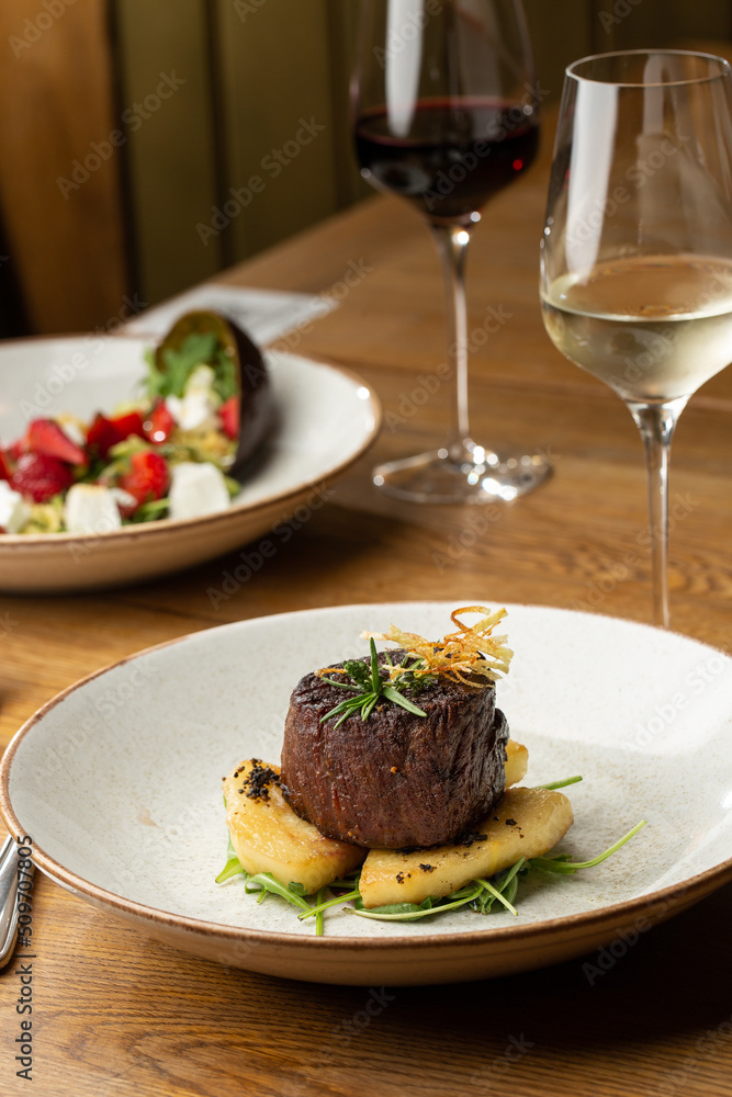 Grilled meat fillet steak medallion with green sauce, served with pear or apple. On dark background