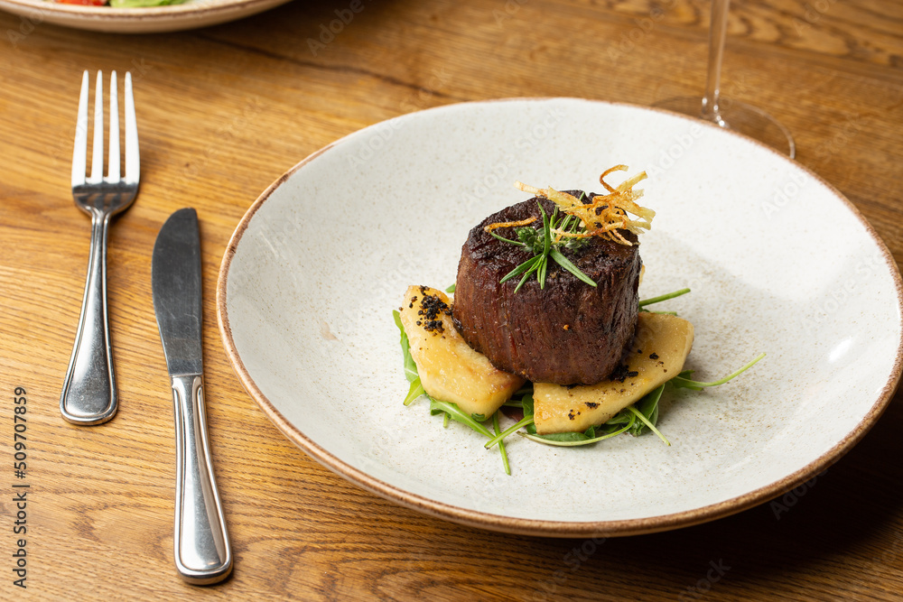 Grilled meat fillet steak medallion with green sauce, served with pear or apple. On dark background