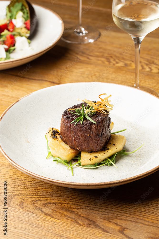 Grilled meat fillet steak medallion with green sauce, served with pear or apple. On dark background