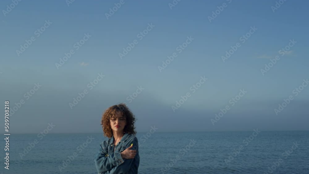 Fashionable girl looking at camera on seaside. Upset woman posing on beach Fashionable girl looking at camera on seaside. Upset woman posing on beach
