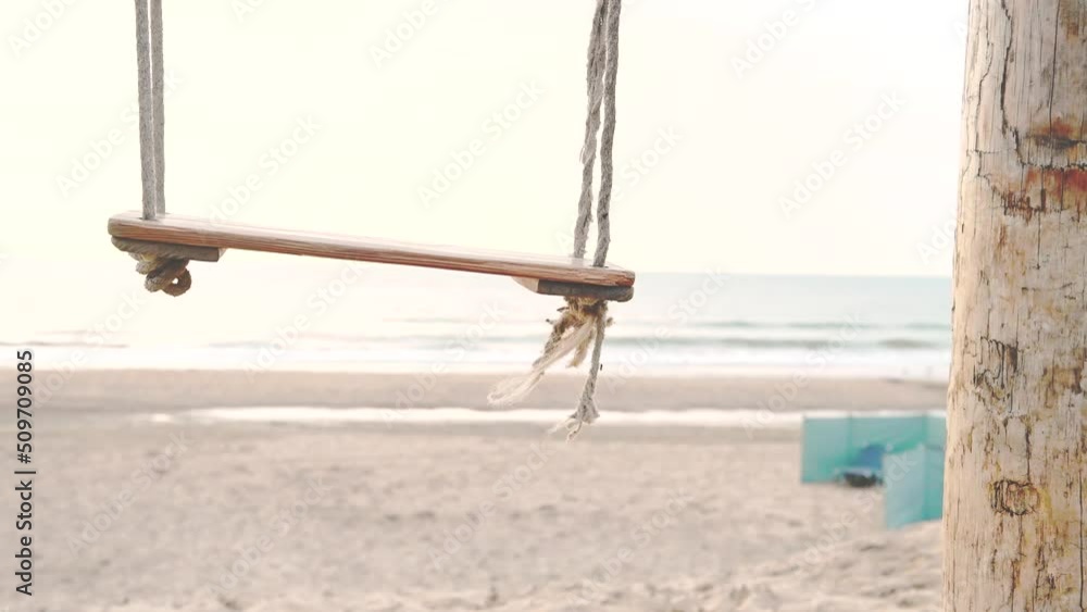 Close up of wooden swings on white sandy beach at sunset. Sea or ocean background, peaceful calm beach 4K summer holiday footage. Close up of wooden swings on white sandy beach at sunset. Sea or ocean background, peaceful calm beach 4K summer holiday footage.
