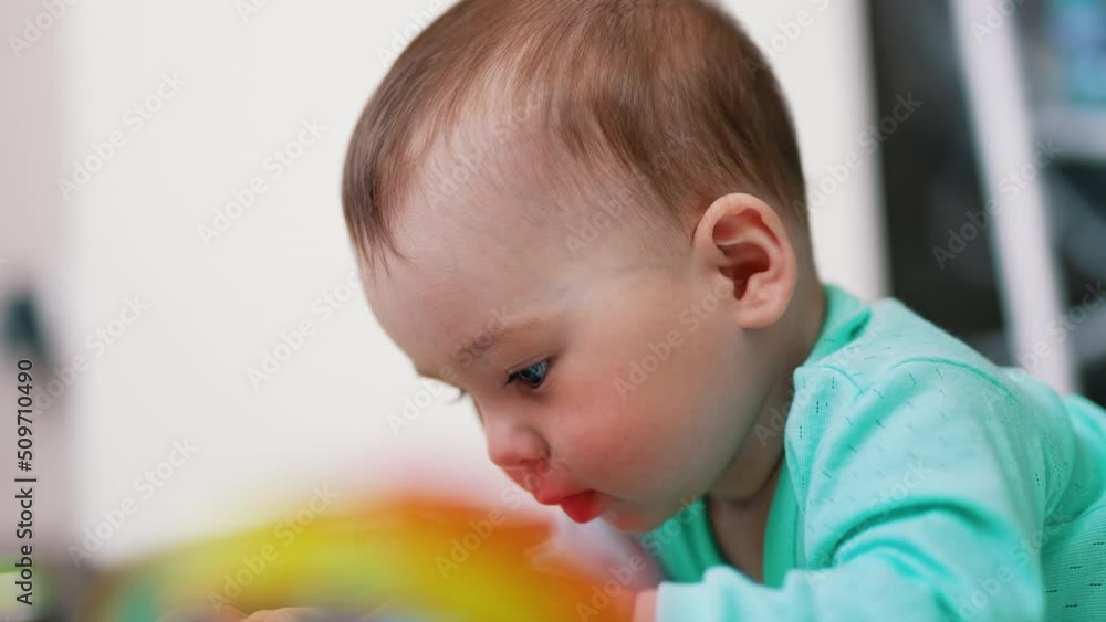 Baby boy with adorable plump cheeks looks down on a toy. Portrait of a cute child interested in play. Close up. Baby boy with adorable plump cheeks looks down on a toy. Portrait of a cute child interested in play. Close up.