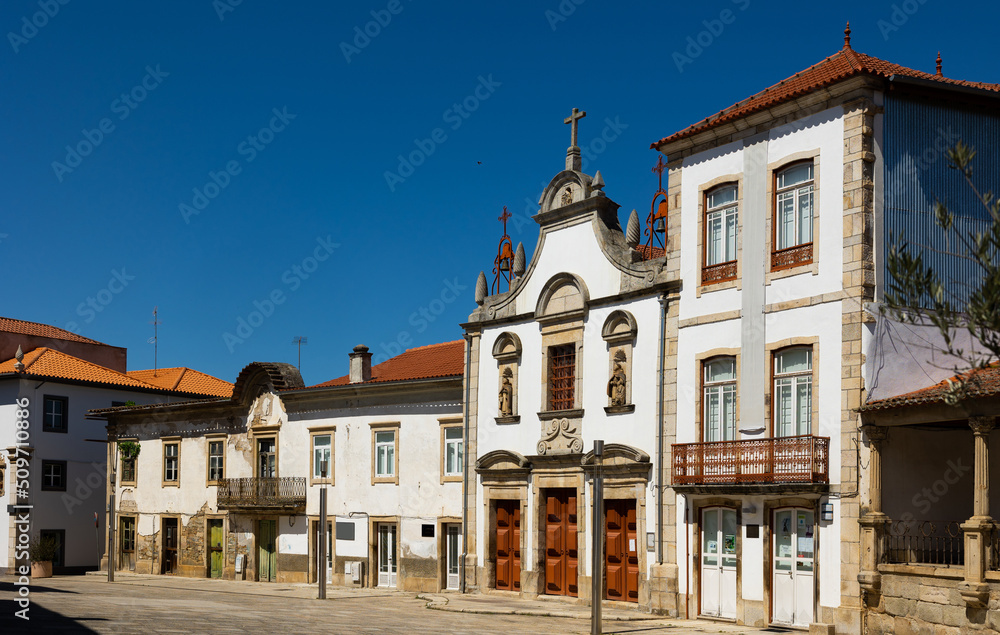 View of residential houses and ancient Church of Mercy on typical paved street in old town of Mirandela in spring, Portugal..