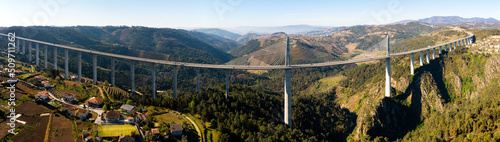 Picturesque panoramic aerial view of high modern suspension viaduct with highway crossing rocky gorge