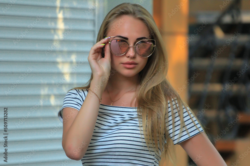 beautiful fashionable blond girl in the city on the park in dress and glasses at summer beautiful fashionable blond girl in the city on the park in dress and glasses at summer