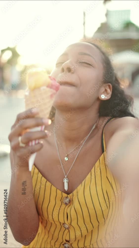 VERTICAL VIDEO: Closeup of smiling young woman with ice cream in her hands making video call on mobile phone on urban city background. Close-up, happy girl using smartphone to communicate. Backlight VERTICAL VIDEO: Closeup of smiling young woman with ice cream in her hands making video call on mobile phone on urban city background. Close-up, happy girl using smartphone to communicate. Backlight