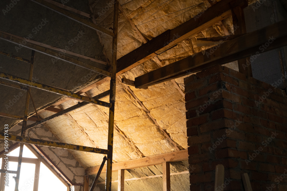 The complex-shaped roof is insulated with yellow glass wool and green mineral wool. Roof insulation technology. Scaffolding. The complex-shaped roof is insulated with yellow glass wool and green mineral wool. Roof insulation technology. Scaffolding.