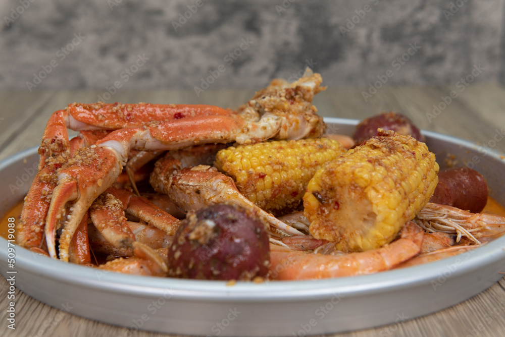 Delicious buttery plate of boiled snow crab legs with corn on the cob and sausage for a tasty seafood meal