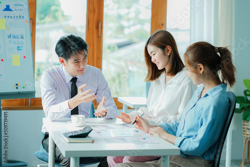 Photography Asian and Caucasian corporate executives discuss business in a conference room of three young businessmen and women discussing tech startups about product roadmaps, and collaboration ideas