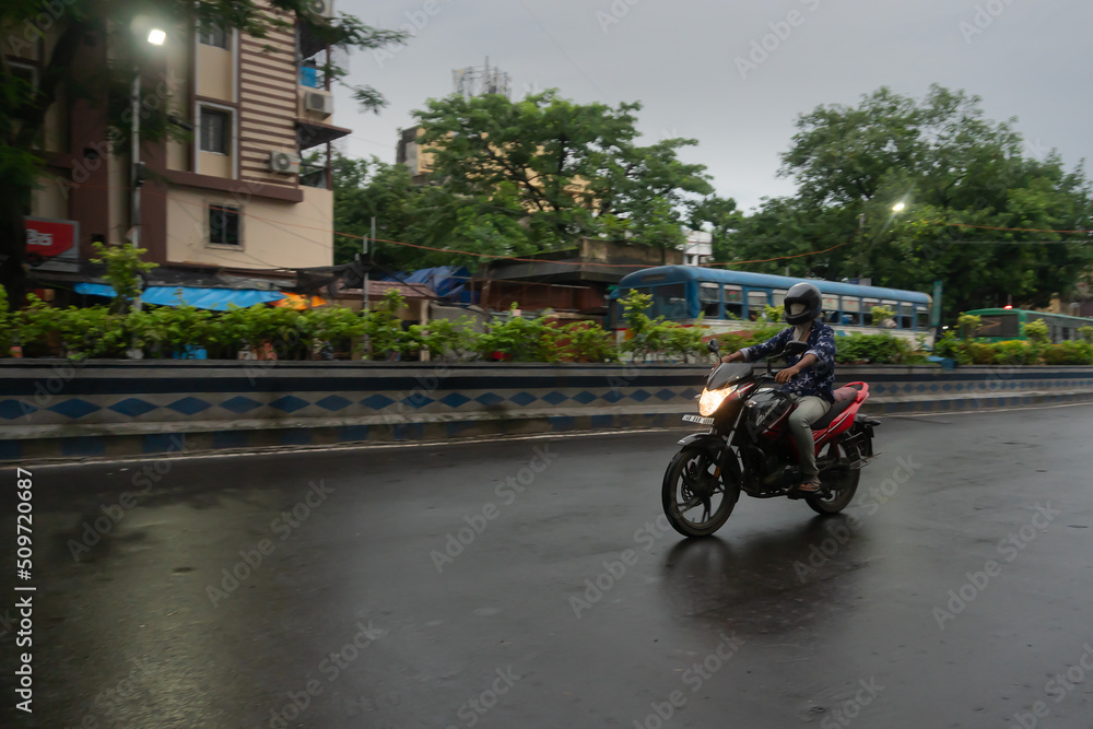 Kolkata, West Bengal, India - 4th August 2020 : View of Kolkata traffic in monsoon. Bike rider passing. Kolkata , being the capital of westbengal , have the maximum traffic of the state.