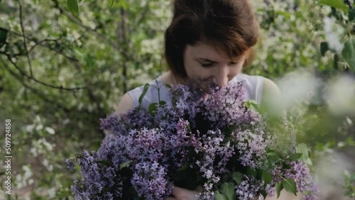 A large basket with garden fresh spring flowers in the hands of a woman. A bouquet of lilacs with a krypny plan. photo