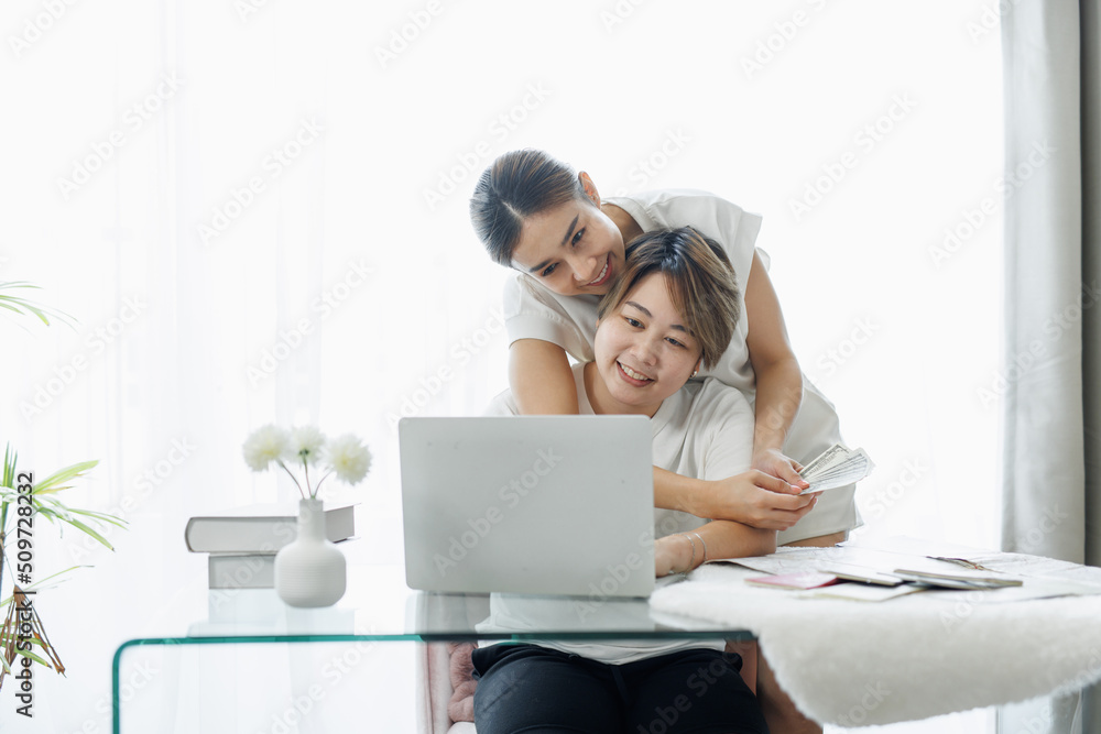 Happy lgbt gay couple of Asian women having fun using a computer laptop at home - LGBT lesbian relationship, Asian LGBTQ female lesbian concept.