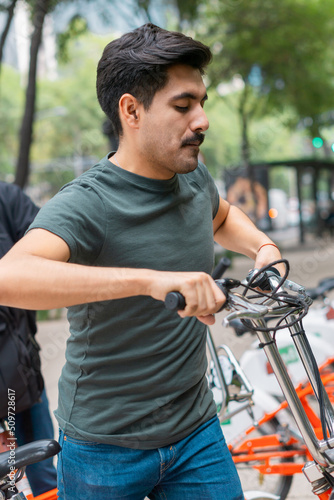 Young man with mustache using a bicycle in the park.