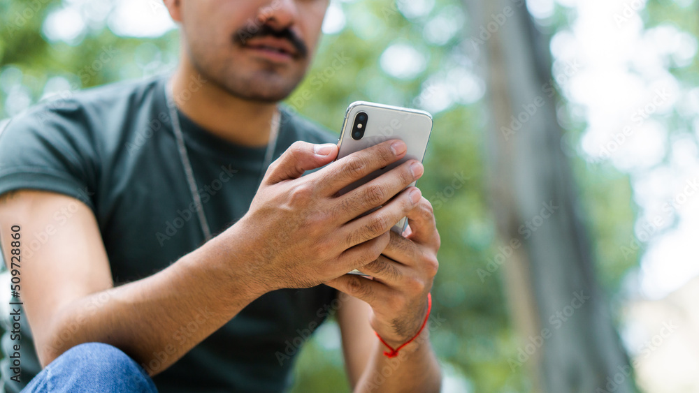 Unrecognizable man in park texting on smartphone. Unrecognizable man in park texting on smartphone.