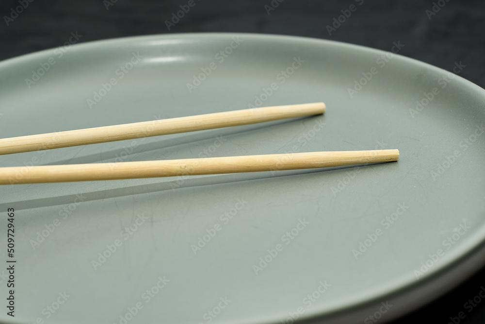 grey plate and chopsticks on a black background grey plate and chopsticks on a black background