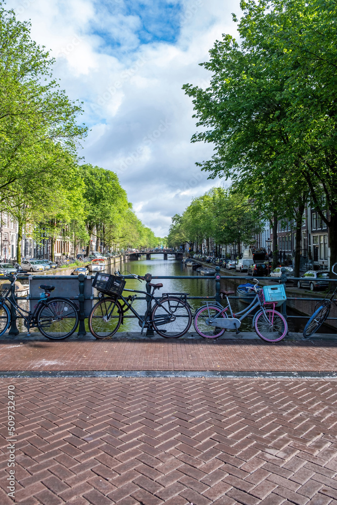 Amsterdam, Netherlands. Parked bikes on a bridge over canal and moored boats on water.