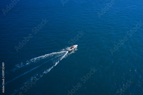 Top view of the boat. Top view of a white boat sailing in the blue sea. A boat with a motor on blue water. Aerial view luxury motor boat. © Berg