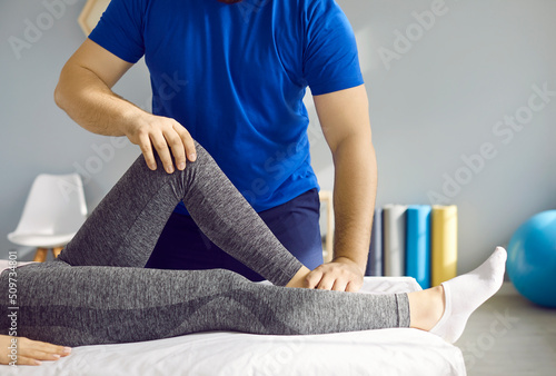 Print op canvas Chiropractor or physiotherapy specialist at rehabilitation center or massage room examining leg of young woman and checking her knee flexion