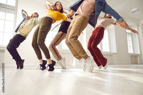 Group of young hip hop dancers rehearse together and learn new choreography in dance studio. Talented young people in casual clothes who are standing on their toes same time. Concept of modern dance