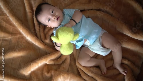 Baby with pampers roll over the body and hold yellow duck toy photo