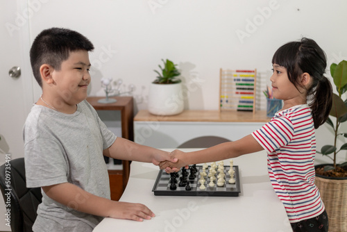 Little boy and little girl are playing chess at home.Children playing chess