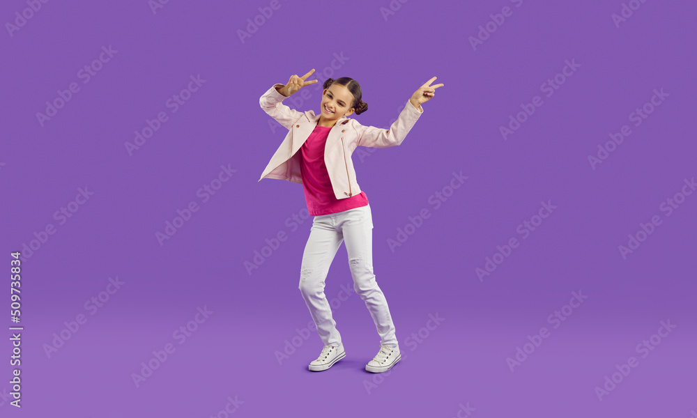Funny active caucasian preteen girl in casual outfit cheerfully waves her arms showing V-sign. Cheerful girl laughing, having fun and fooling around on purple background. Full length. Web banner.