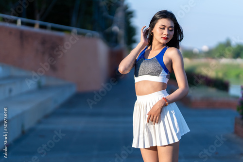 Portrait of beautiful athletic young asian woman in fashionable sportswear standing and having rest after strong exercise training in garden the park,Outdoor Sporty concept © Thinapob