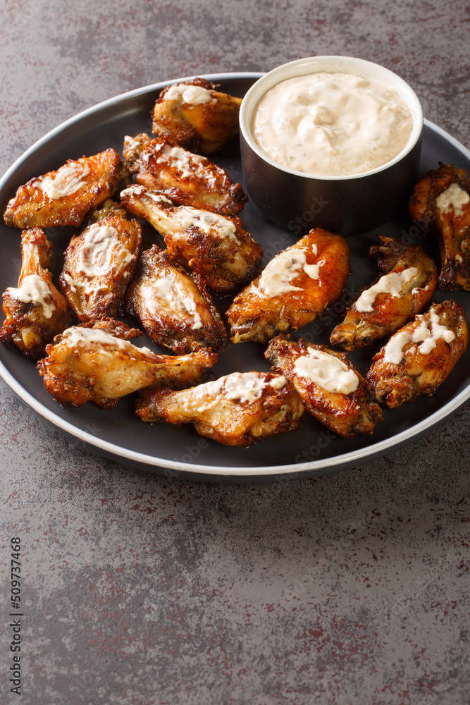 Grilled chicken wings with Alabama white sauce close-up in a plate on the table. Vertical Grilled chicken wings with Alabama white sauce close-up in a plate on the table. Vertical