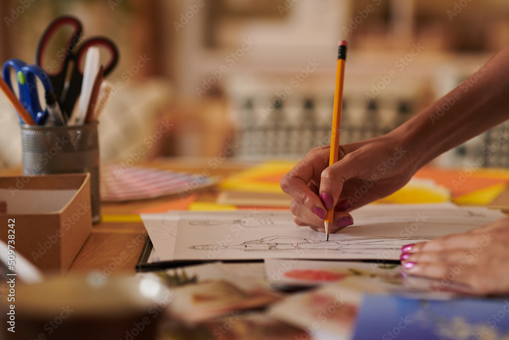 Close-up image of fashion designer drawing sketch at her desk in studio Close-up image of fashion designer drawing sketch at her desk in studio