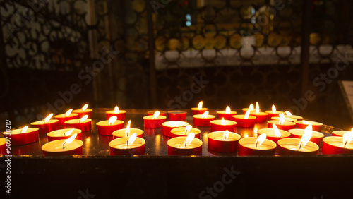Fotografia Perspective of a multitude of burning candles with flames in a italian cathedral, posed by believers after a prayer