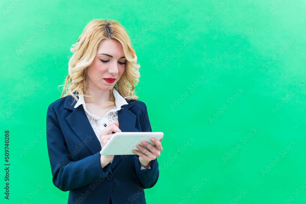 Elegant businesswoman looking holding in hand digital tablet – business young woman using technology – professional person looking digital tablet – isolated on green background Elegant businesswoman looking holding in hand digital tablet – business young woman using technology – professional person looking digital tablet – isolated on green background