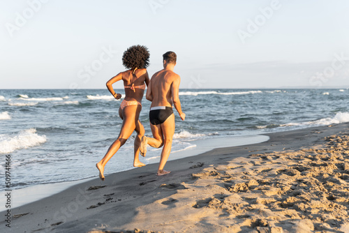 Happy Young couple run on beach at sunset – loving couple walk on beach holiday – People on seaside in summer – beach summer vacation fun couple 