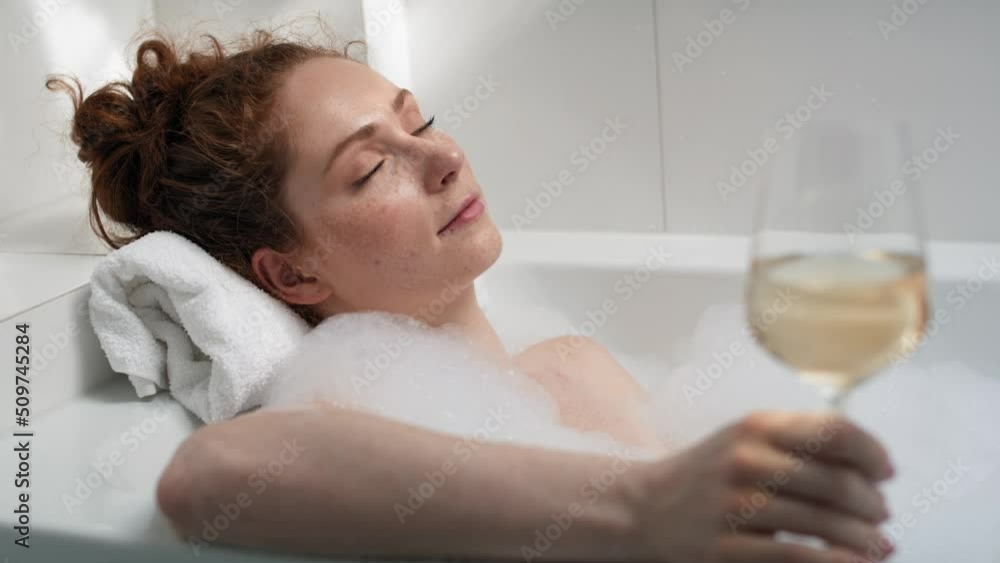 Caucasian redhead woman taking a bath and drinking wine. Shot with RED helium camera in 4K. Caucasian redhead woman taking a bath and drinking wine. Shot with RED helium camera in 4K.
