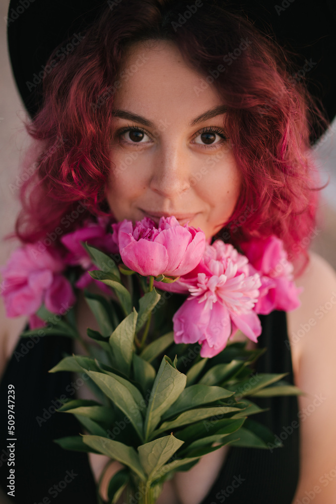 Young woman with pink hair holding bunch of peonies on the beach. Young woman with pink hair holding bunch of peonies on the beach.
